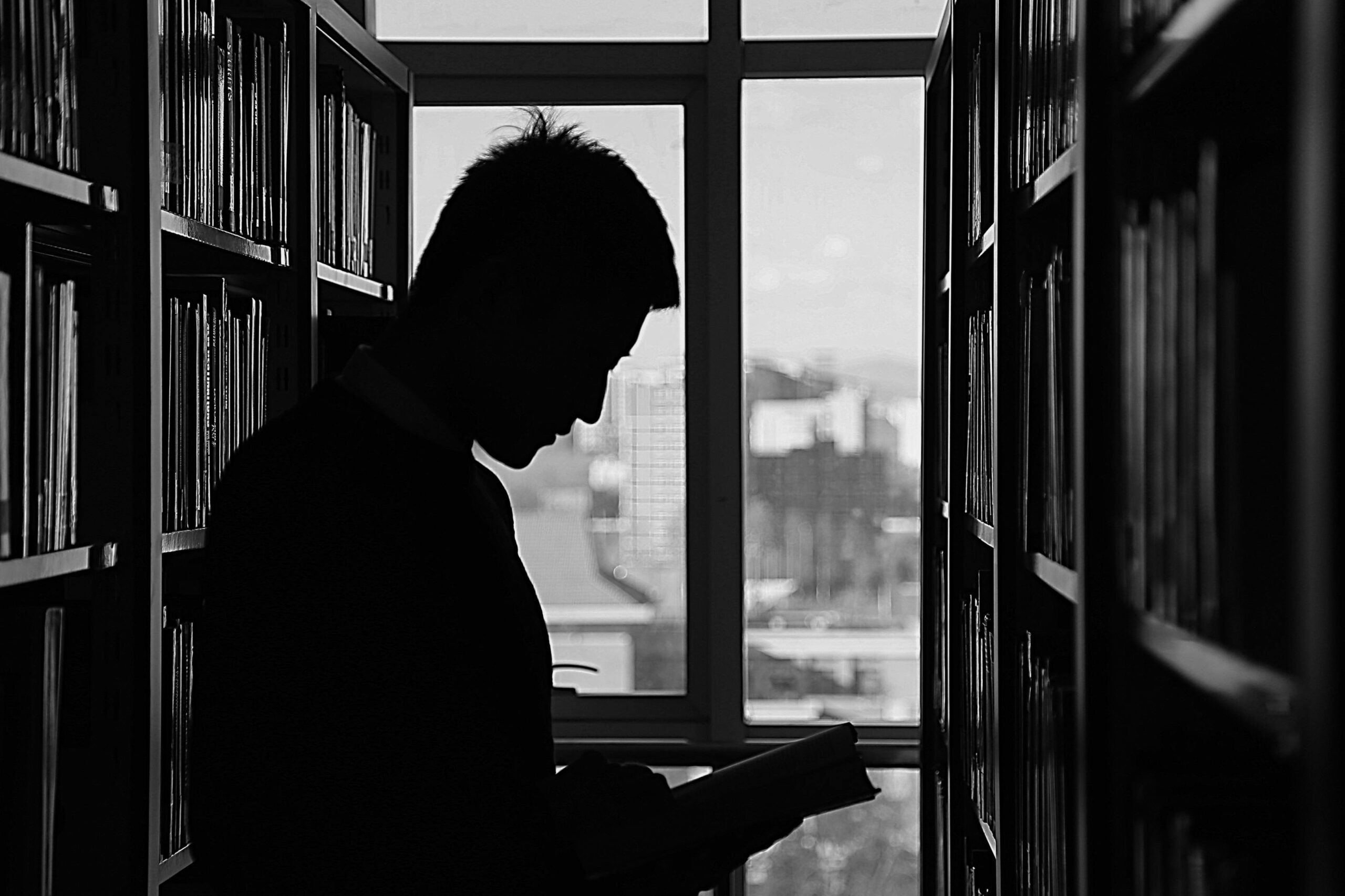 Reader silhouette in a monochrome library setting