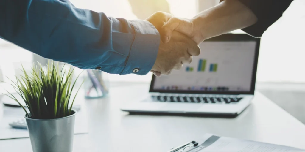 Chris Spurling business growth guide symbolized by partners shaking hands in an office.